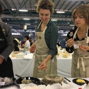 Synne står foran et ostebord i en konkurranse for kåring av verdens beste ost